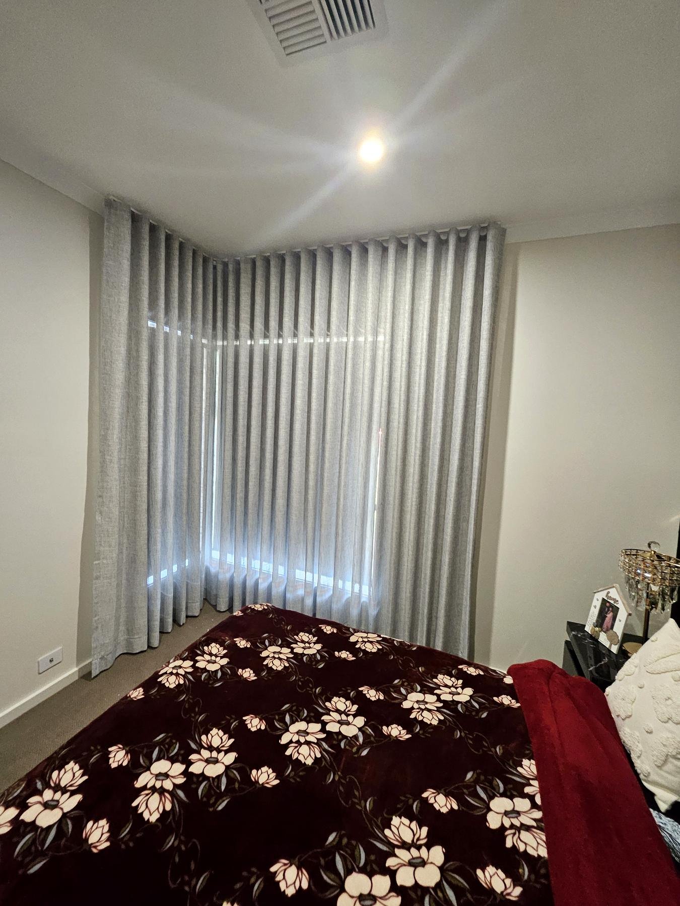Grey curtains wrapping a corner bedroom window
