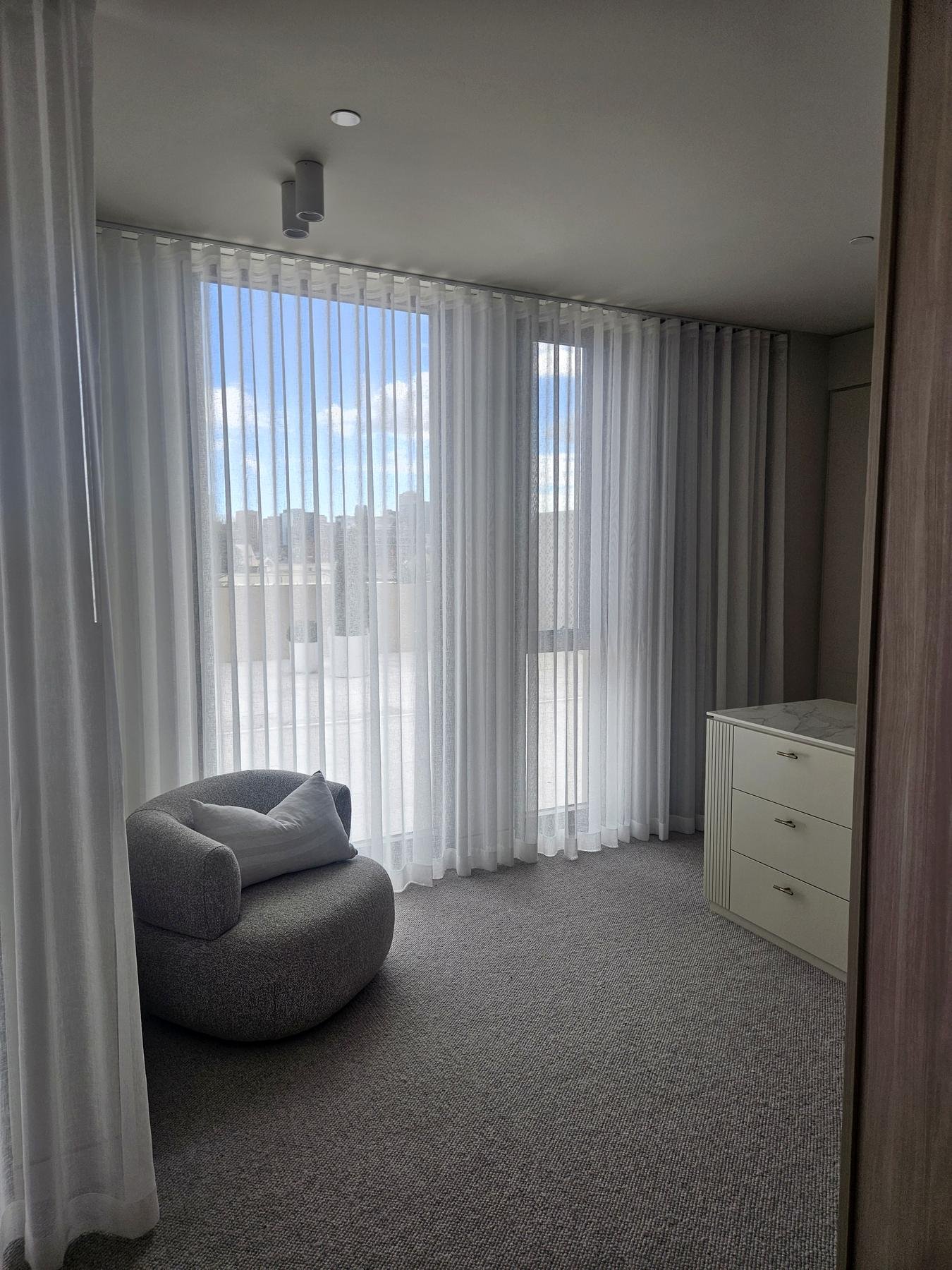 Sheer curtains over a bedroom sliding door with a garden view
