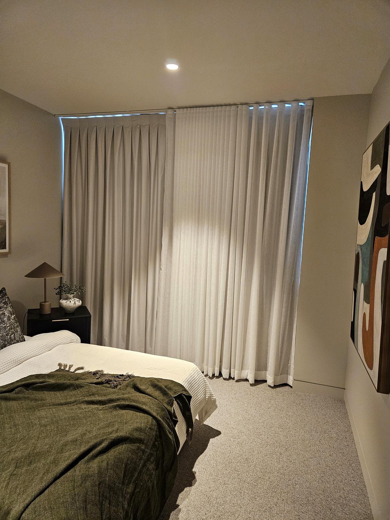 Floor-to-ceiling sheer wave-fold curtains beside a bed