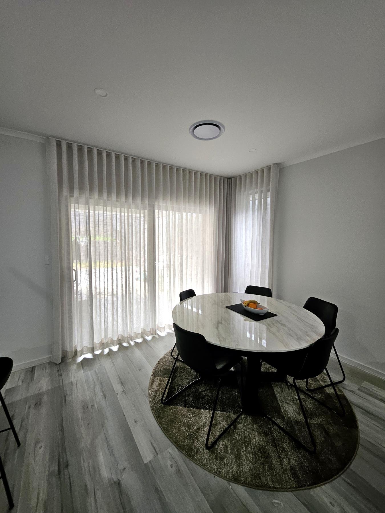 Sheer curtains behind a round dining table