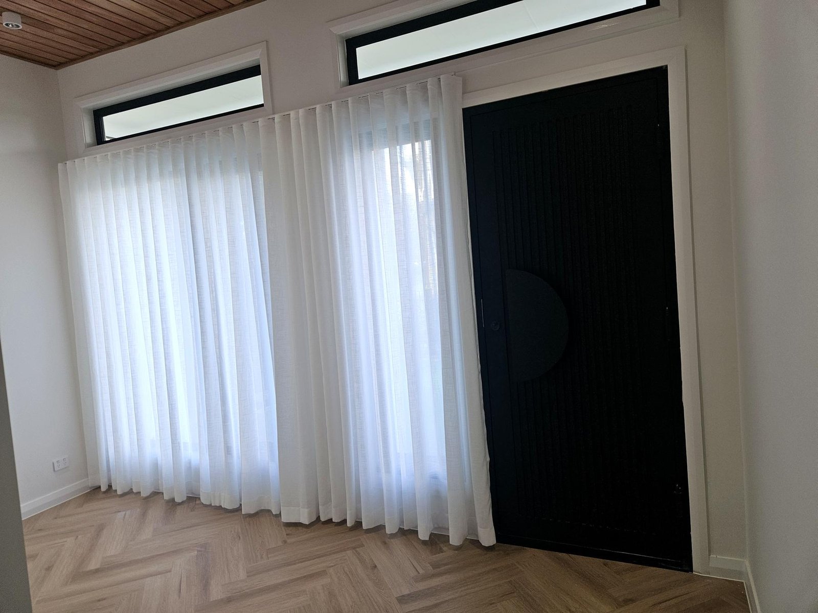 White sheer curtains beside a black feature door