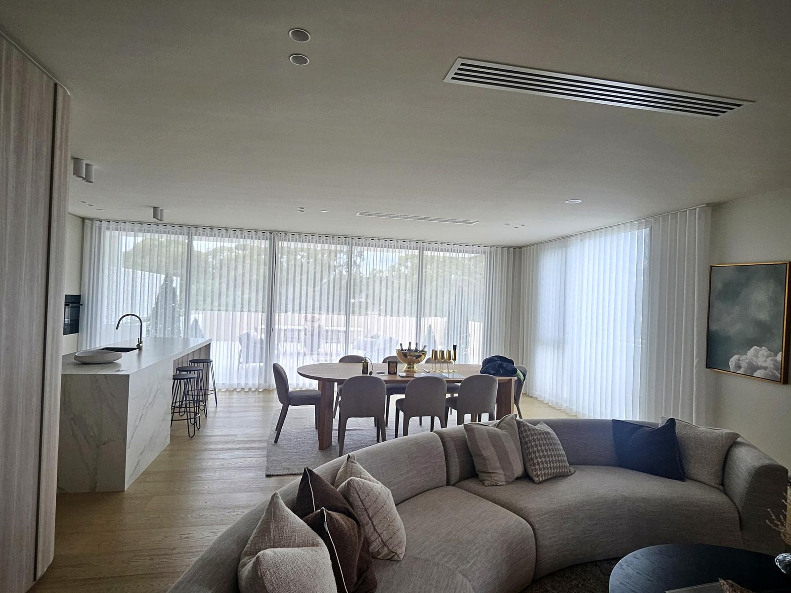 Sheer curtains along the windows of an open-plan living area
